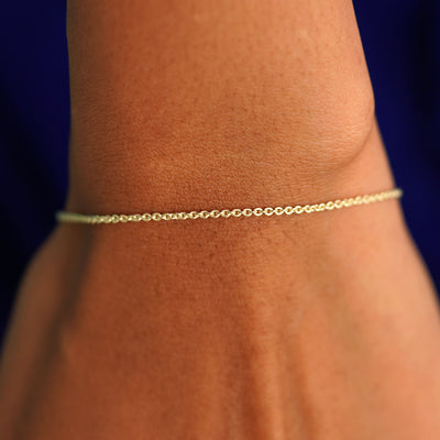 A model's wrist wearing a solid yellow gold Thick Cable Bracelet