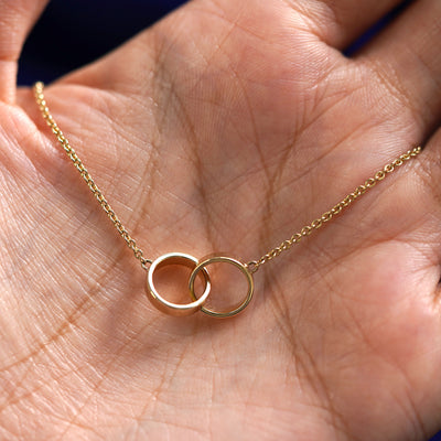 A yellow gold Bound Together Necklace draped on a model's palm