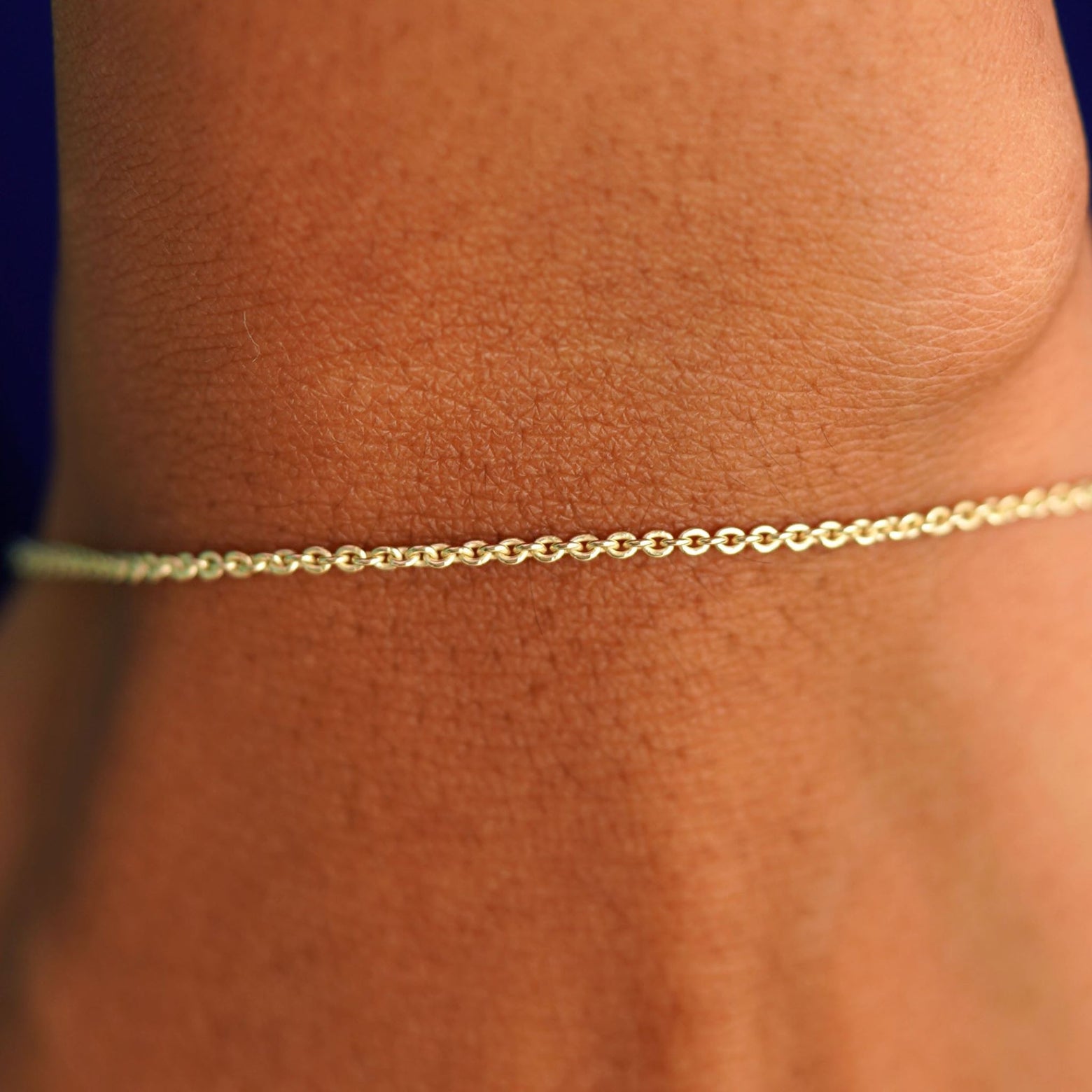 Close up view of a model's wrist wearing a solid yellow gold Thick Cable Bracelet