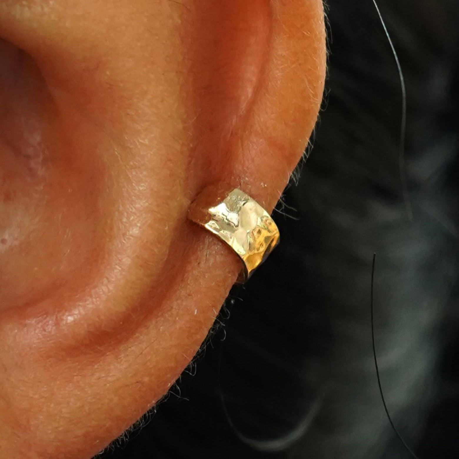 Close up view of a model's ear wearing a 14k gold Hammered Thick Cuff