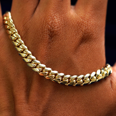 A solid gold Miami Cuban Chain resting on the back of a model's hand