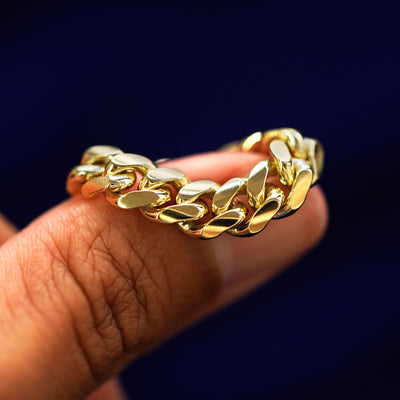 A yellow gold Miami Ring draped over a model's finger to show the flexibility of the chain