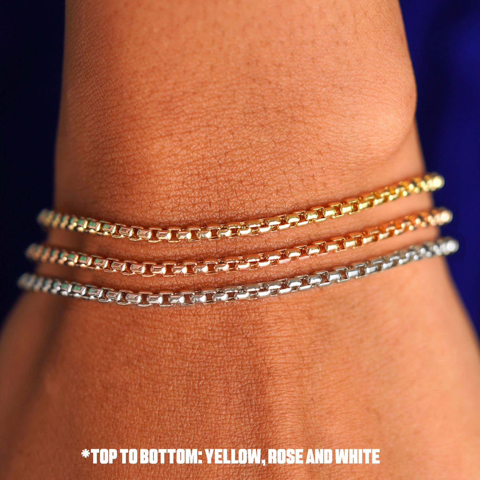 Close up view of a model's wrist wearing three versions of the Round Box Bracelet in options of rose, yellow, and white gold