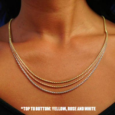 Close up view of a model's neck wearing three versions of the Round Box Chain in options of rose, yellow, and white gold