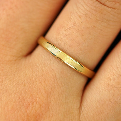 Close up view of a model's hand wearing a solid yellow gold Beveled Edge Band