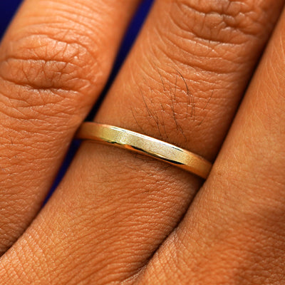 Close up view of a model's fingers wearing a 14k yellow gold Beveled Edge Band