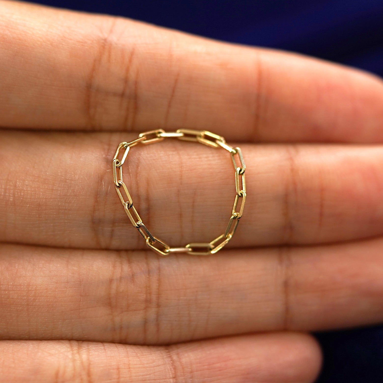 A yellow gold Butch Chain Ring in a model's hand showing the thickness of the chain