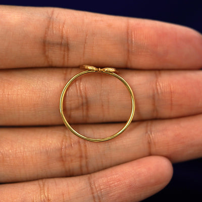 A yellow gold Butterfly Ring in a model's hand showing the thickness of the band