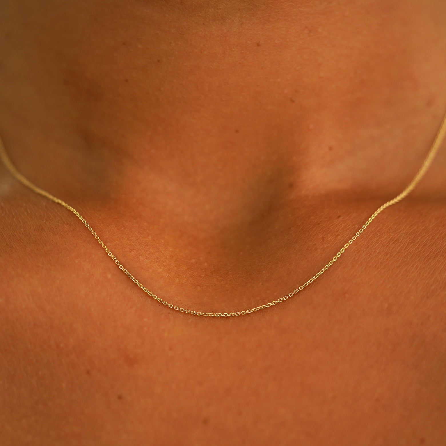 Close up view of a model's neck wearing a 14k yellow gold Cable Chain