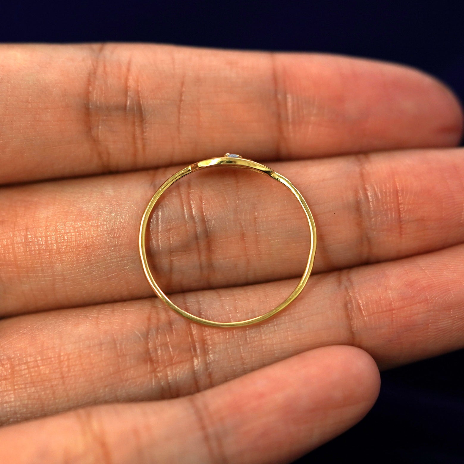 A yellow gold Diamond Evil Eye Ring in a model's hand showing the thickness of the band