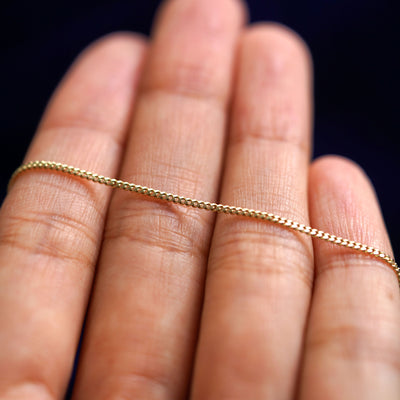 A yellow gold Mini Miami Bracelet resting on a model's fingers