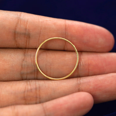 A yellow gold Shimmer Ring in a model's hand showing the thickness of the band