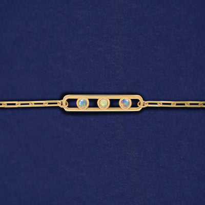 A yellow gold elongated open oval link with three bezel set Opals inside on a 14k gold Butch chain bracelet