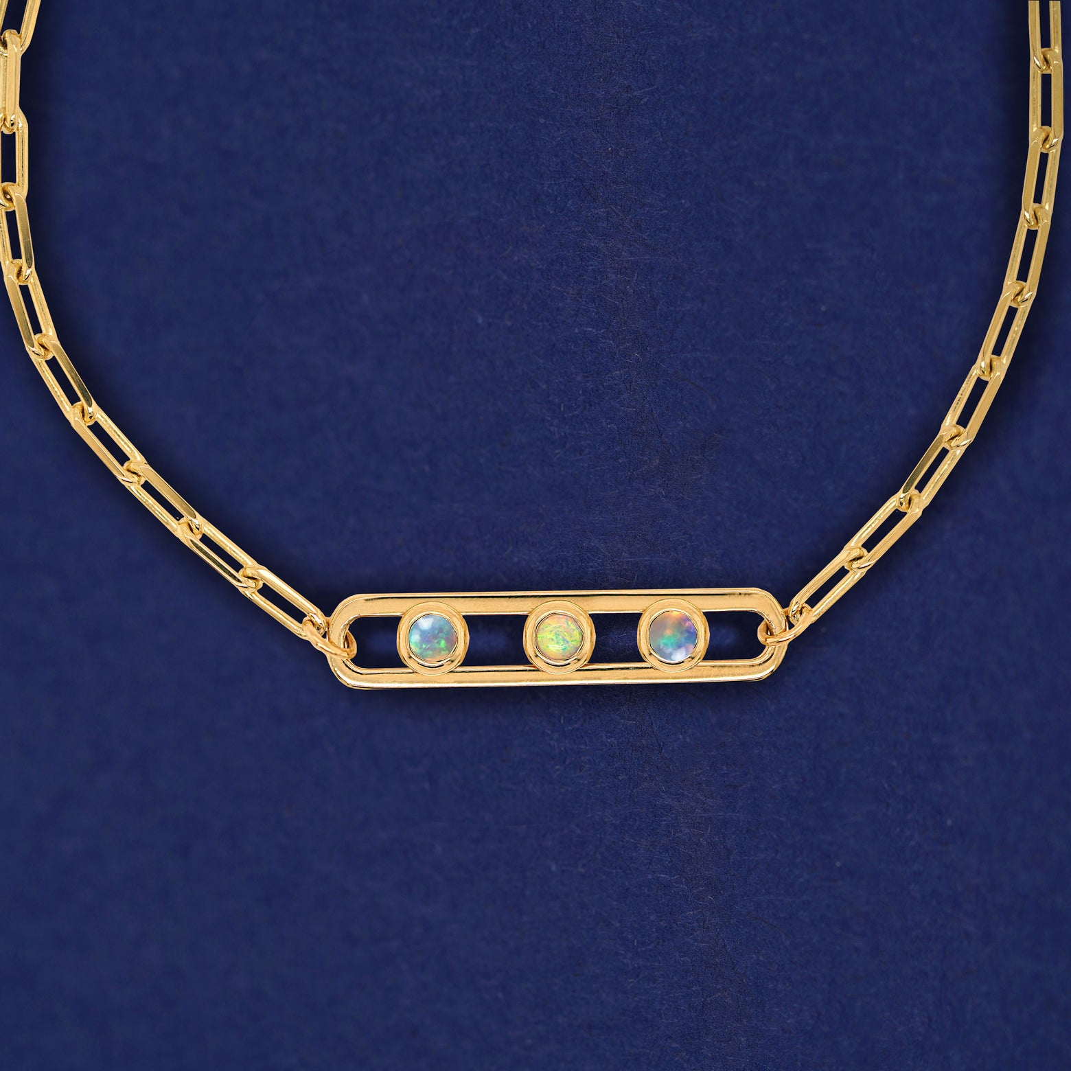 A yellow gold elongated open oval link with three bezel set Opals inside on a 14k gold Butch chain necklace