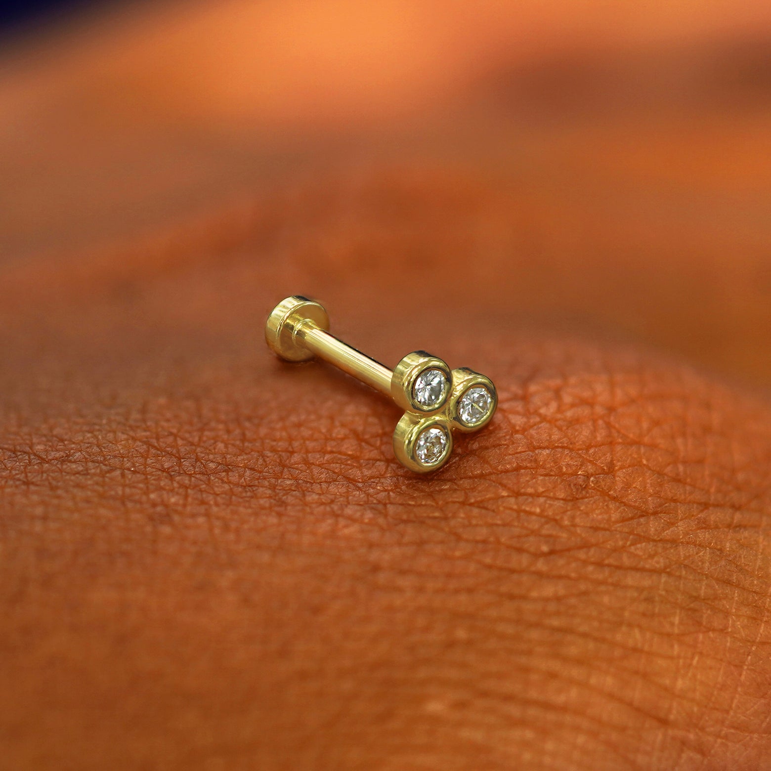 A solid 14k yellow gold Diamond Trio Flatback on the back of a model's hand