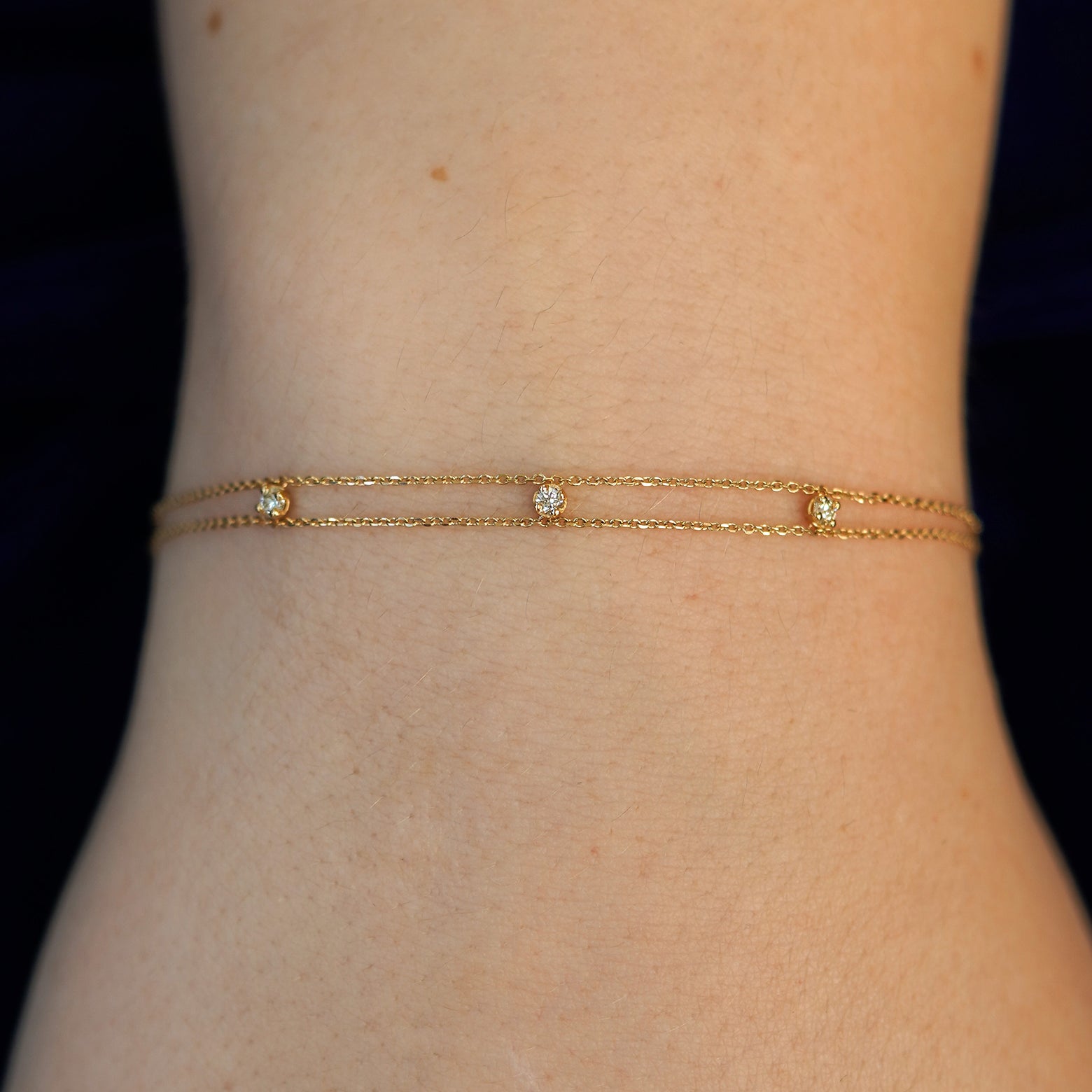 A model's wrist wearing a solid gold 3 Diamond Cable Bracelet