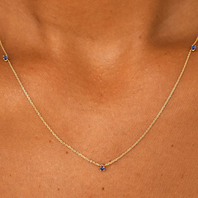 Close up view of a model's neck wearing a solid 14k yellow gold 3 Gemstone Cable Necklace in sapphire