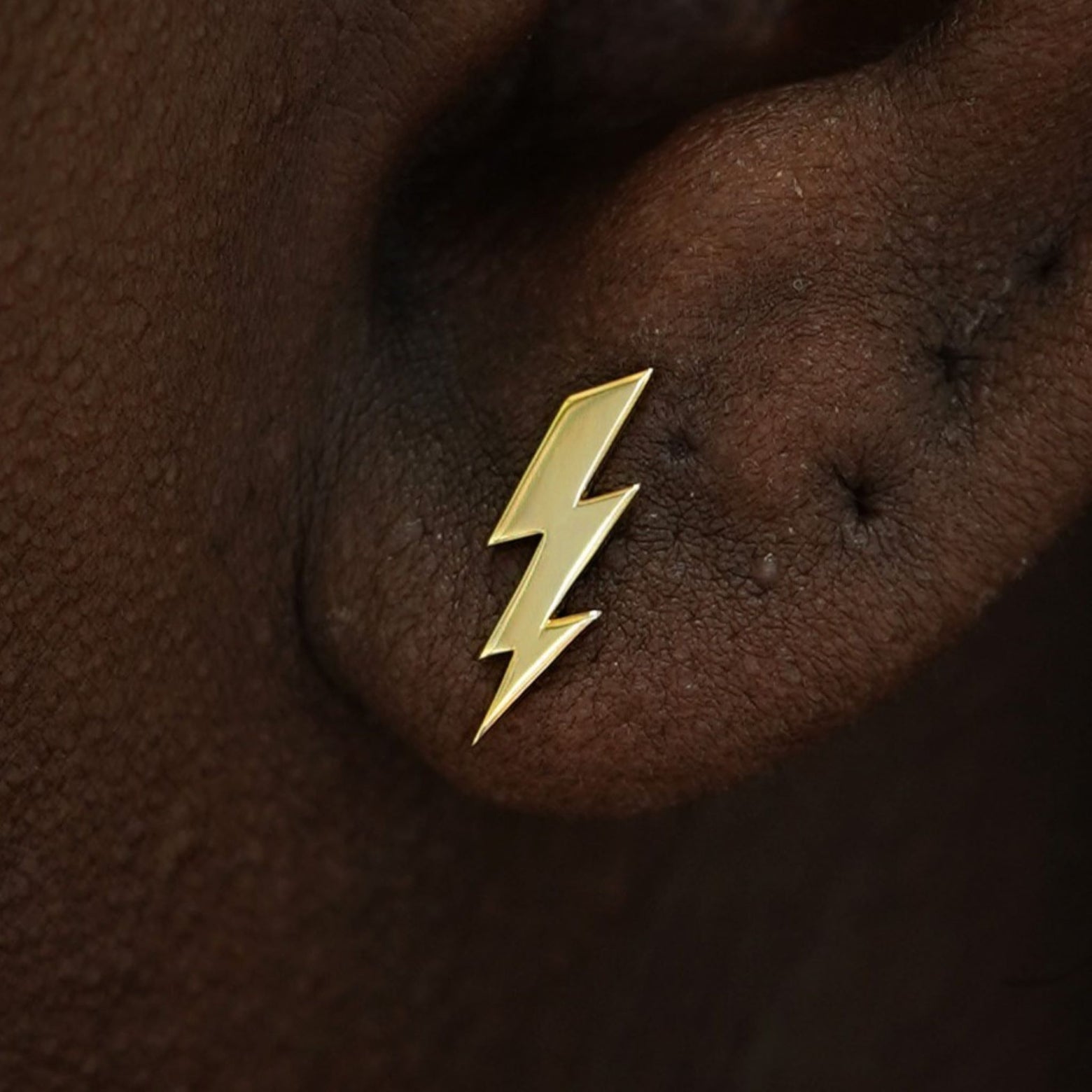 Close up view of a model's ear wearing a 14k gold Lightning Bolt Earring