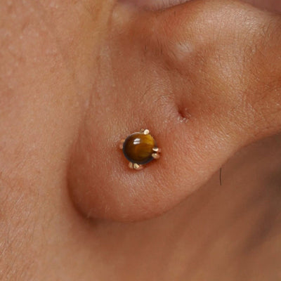 Close up view of a model's ear wearing a 14k yellow gold Tiger Eye Earring