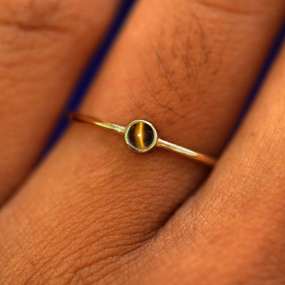 Close up view of a model's fingers wearing a 14k yellow gold Tiger Eye Ring