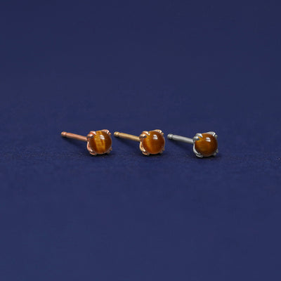 Three versions of the Tiger Eye Earring shown in options of rose, yellow, and white gold