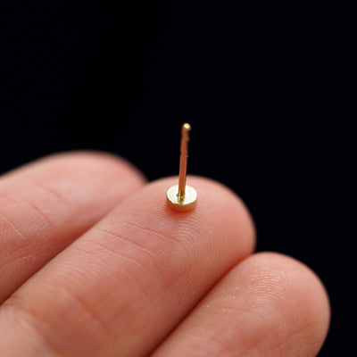 A yellow gold Small Circle Earring laying facedown on a model's fingers to show the underside view