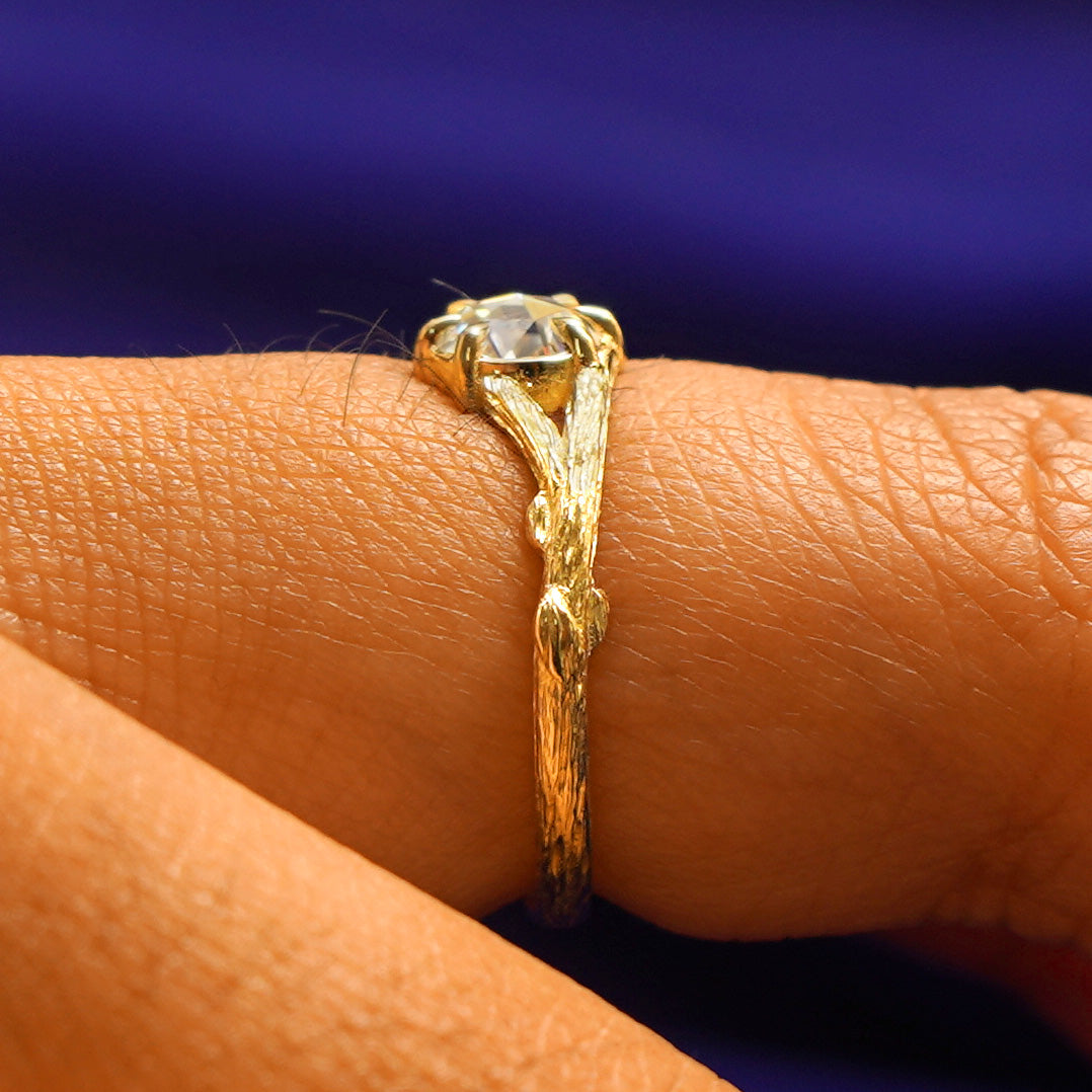 Side view of a Moissanite Branches Ring on a model's finger showing two tree branches going to the center stone