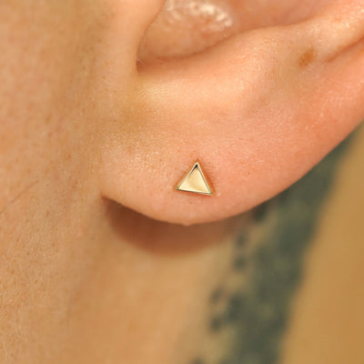 Close up view of a model's ear wearing a 14k gold Triangle Earring