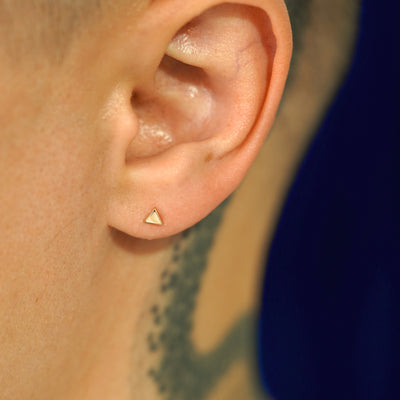 A model's ear wearing a 14k yellow gold Triangle Earring