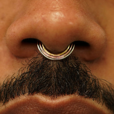 Close up view of a model's nose wearing a 14k gold Rainbow Septum