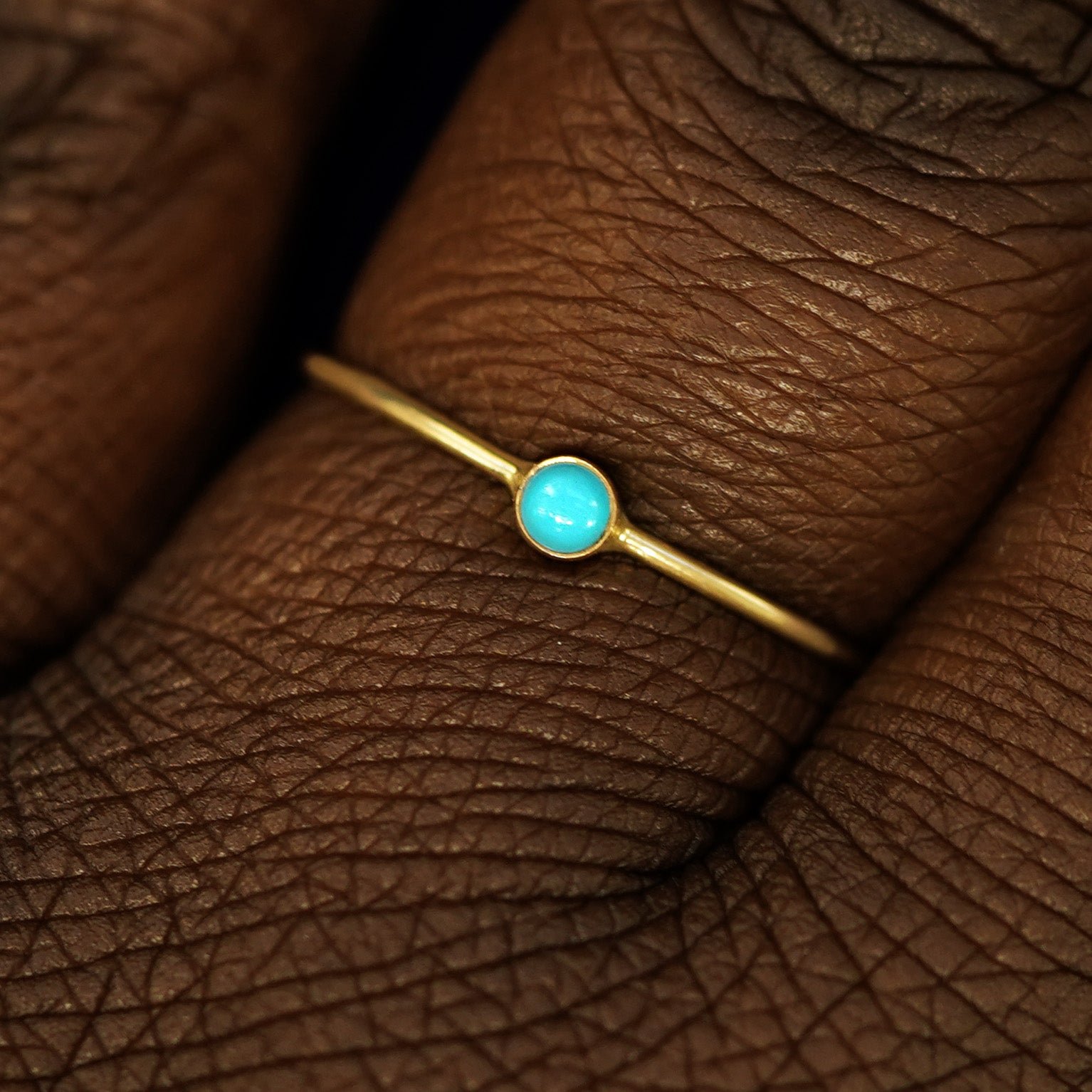 Close up view of a model's fingers wearing a 14k yellow gold Turquoise Ring