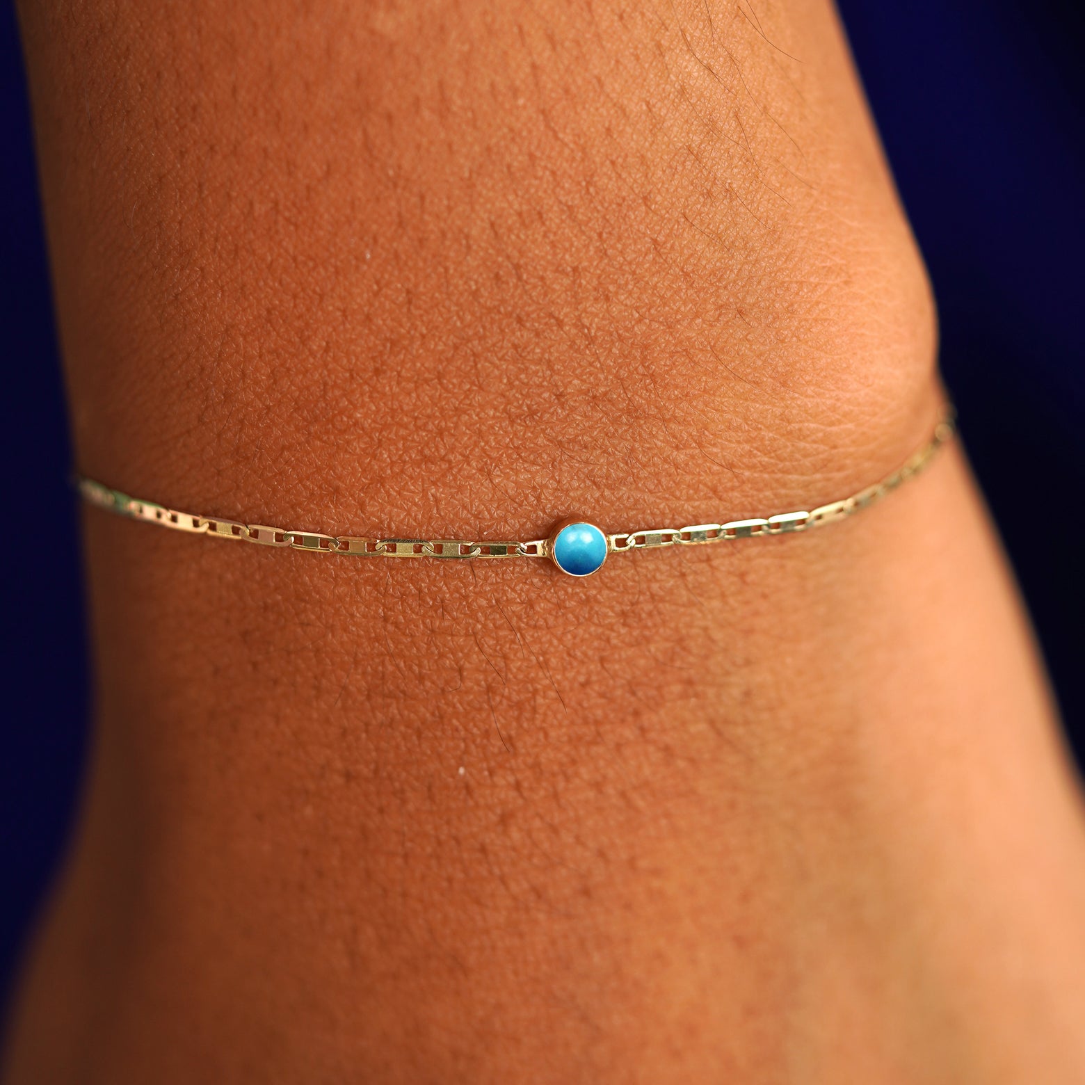 A model's wrist wearing a 14 karat yellow gold Turquoise Bracelet