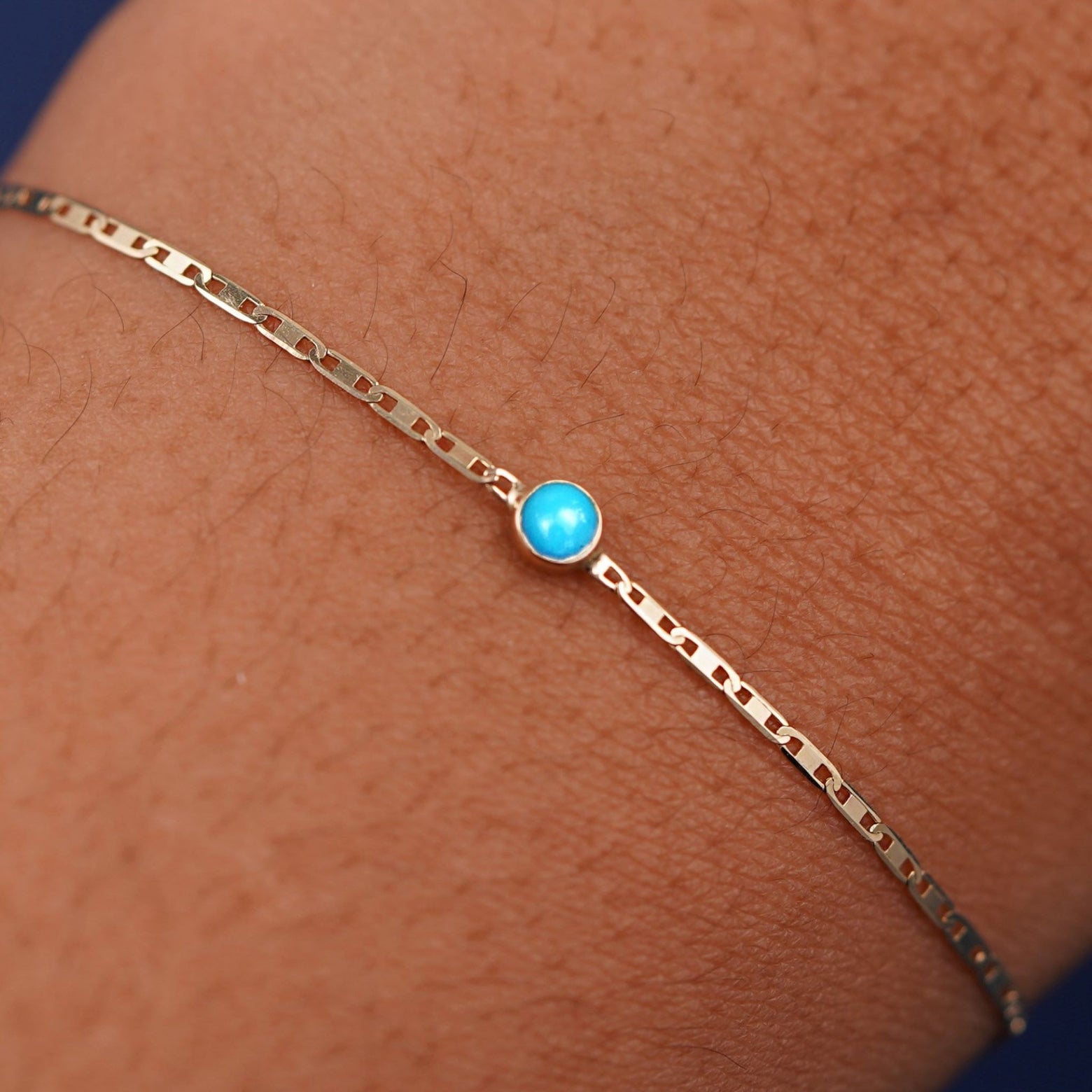 Close up view of a models wrist wearing 14k yellow gold Turquoise Bracelet