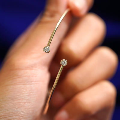 A model holding a 14k yellow gold Diamond Bypass Bangle Bracelet to show the gap in the bangle