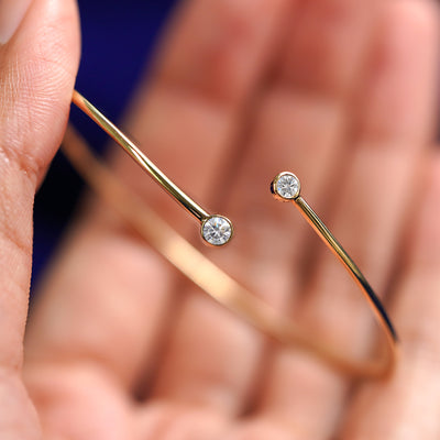 A yellow gold Diamond Bypass Bracelet resting between a model's fingers