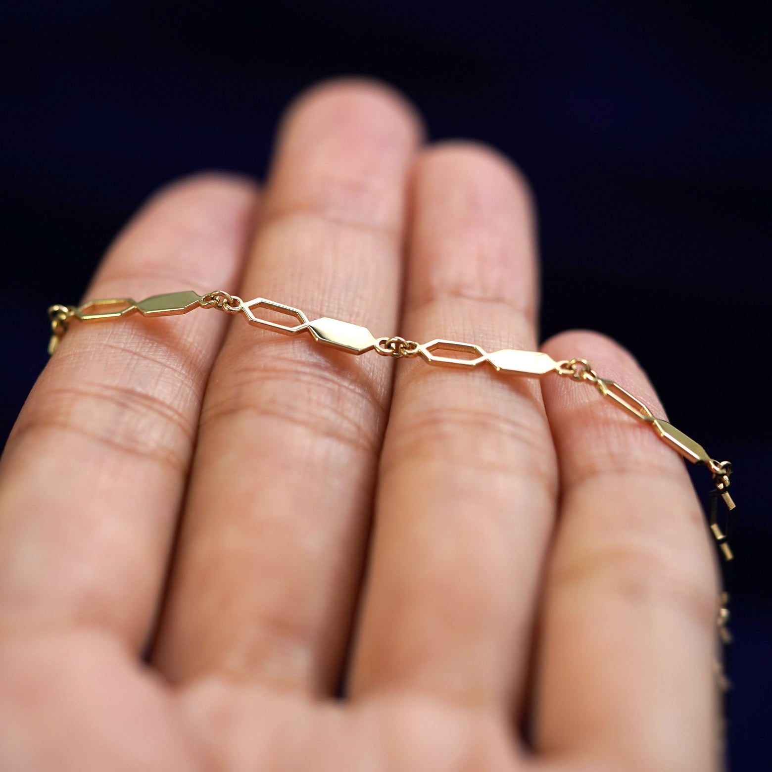 A yellow gold Tanlah Chain resting on a model's fingers
