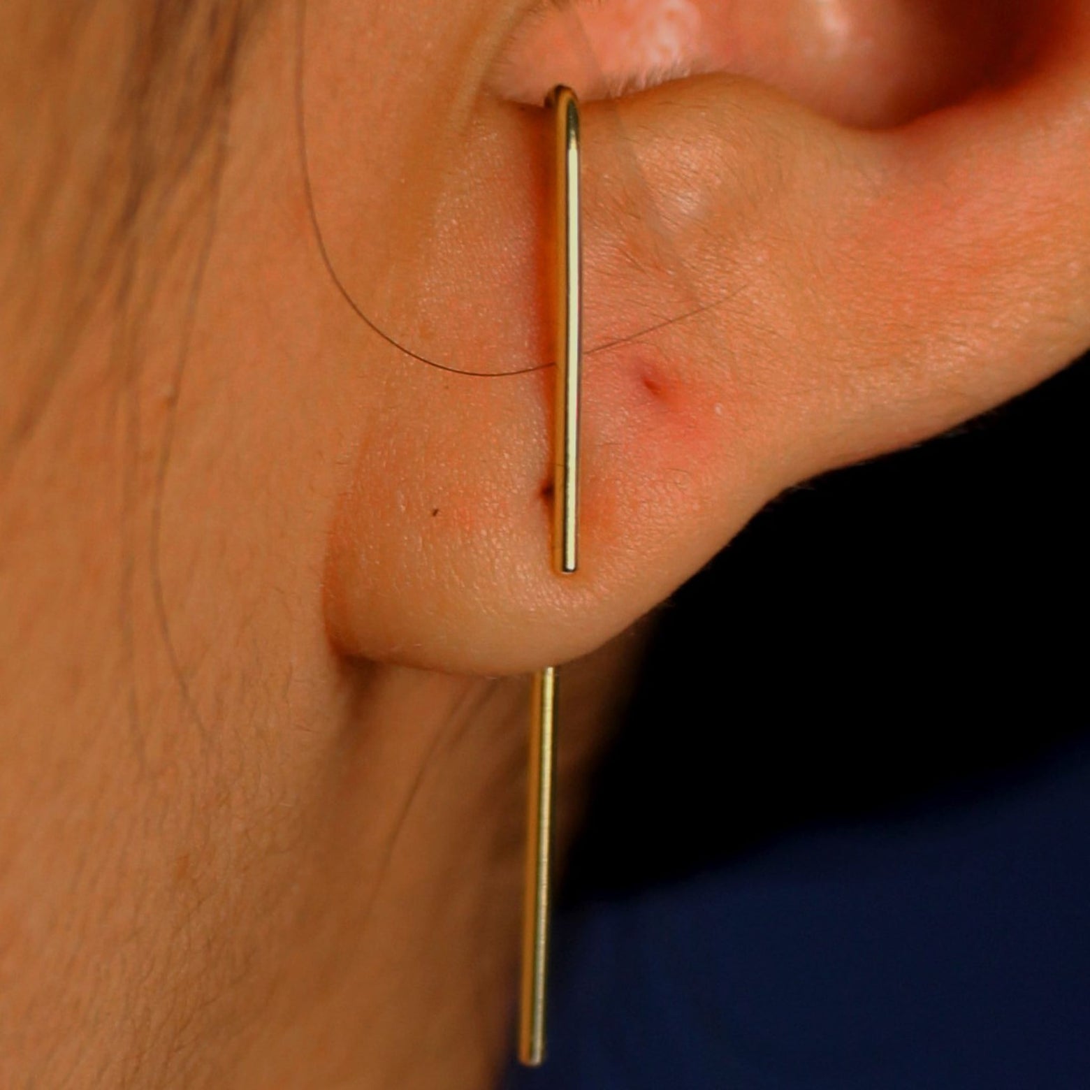 Close up view of a model's ear wearing a yellow gold Line Jacket with a Suspender Earring