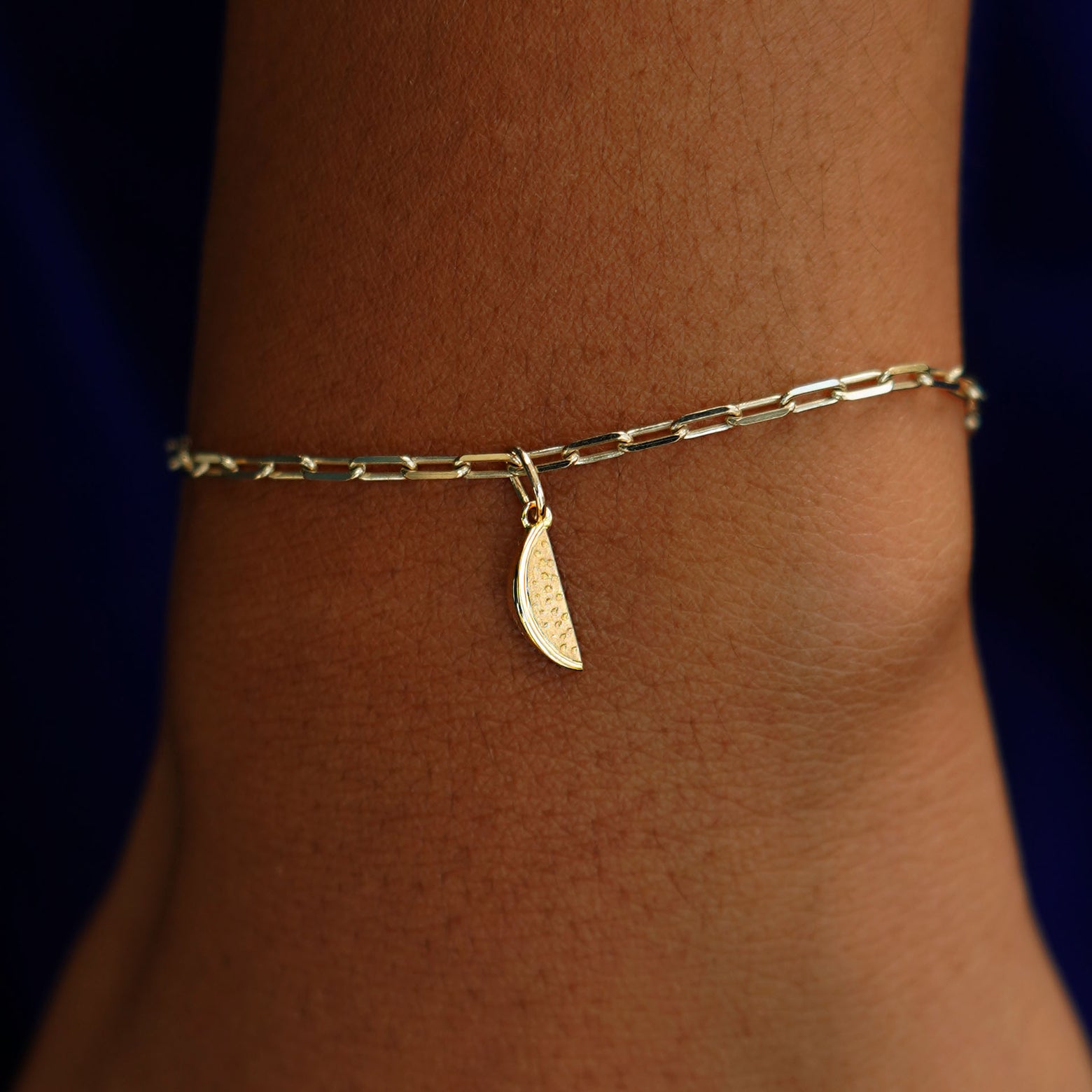 A model's wrist wearing a yellow gold Watermelon Charm on a Butch Bracelet