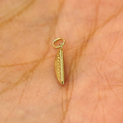 A solid gold Watermelon Charm for chain resting in a model's palm face up to show details