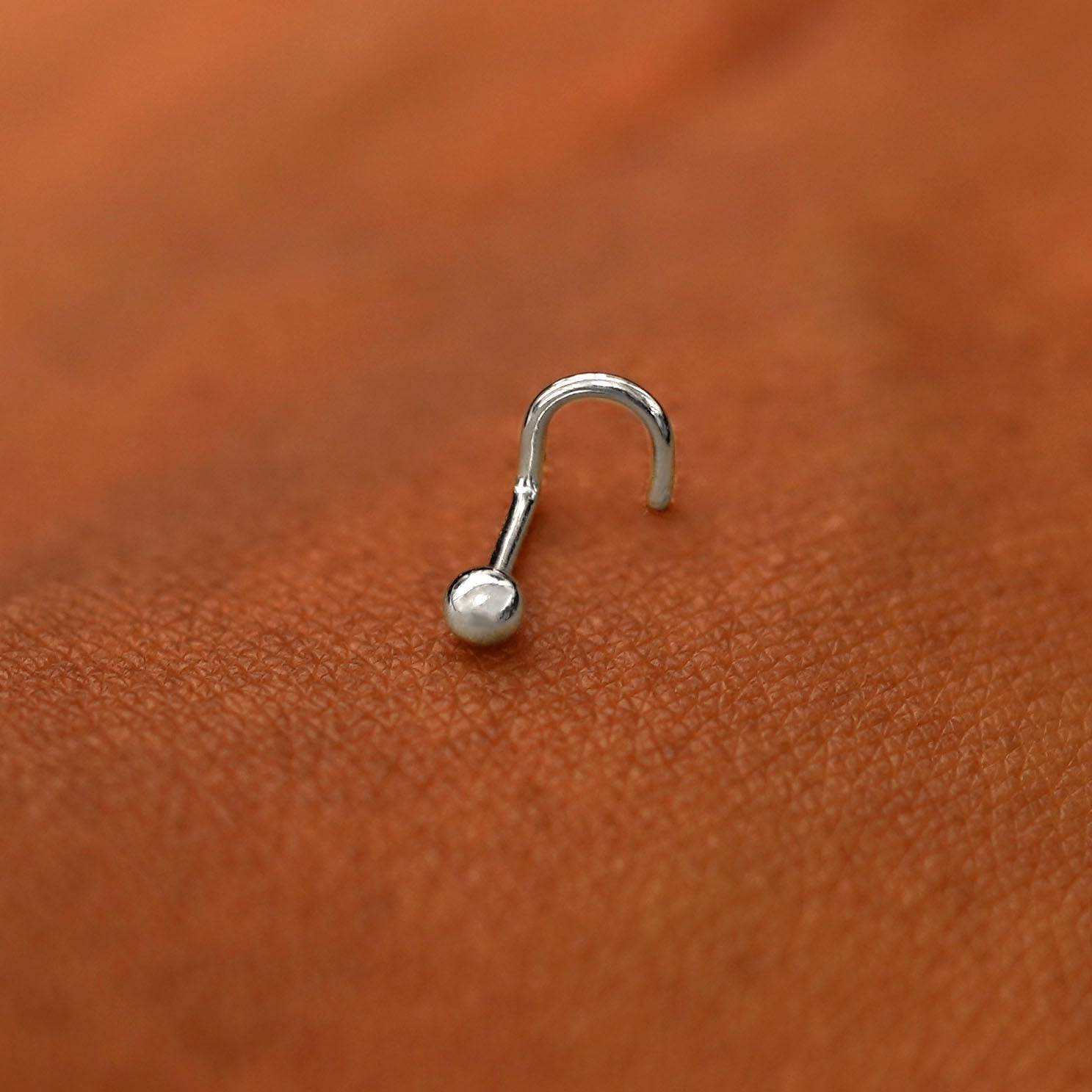 A white gold Ball Nose Stud laying on the back of a model's hand