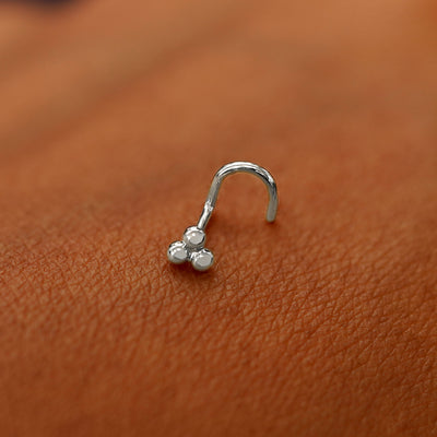 A white gold Ball Trio Nose Stud laying on the back of a model's hand