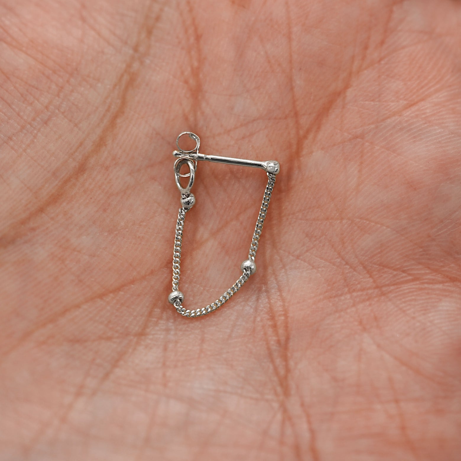 A white gold Beaded Chain Loop Earring in model's palm