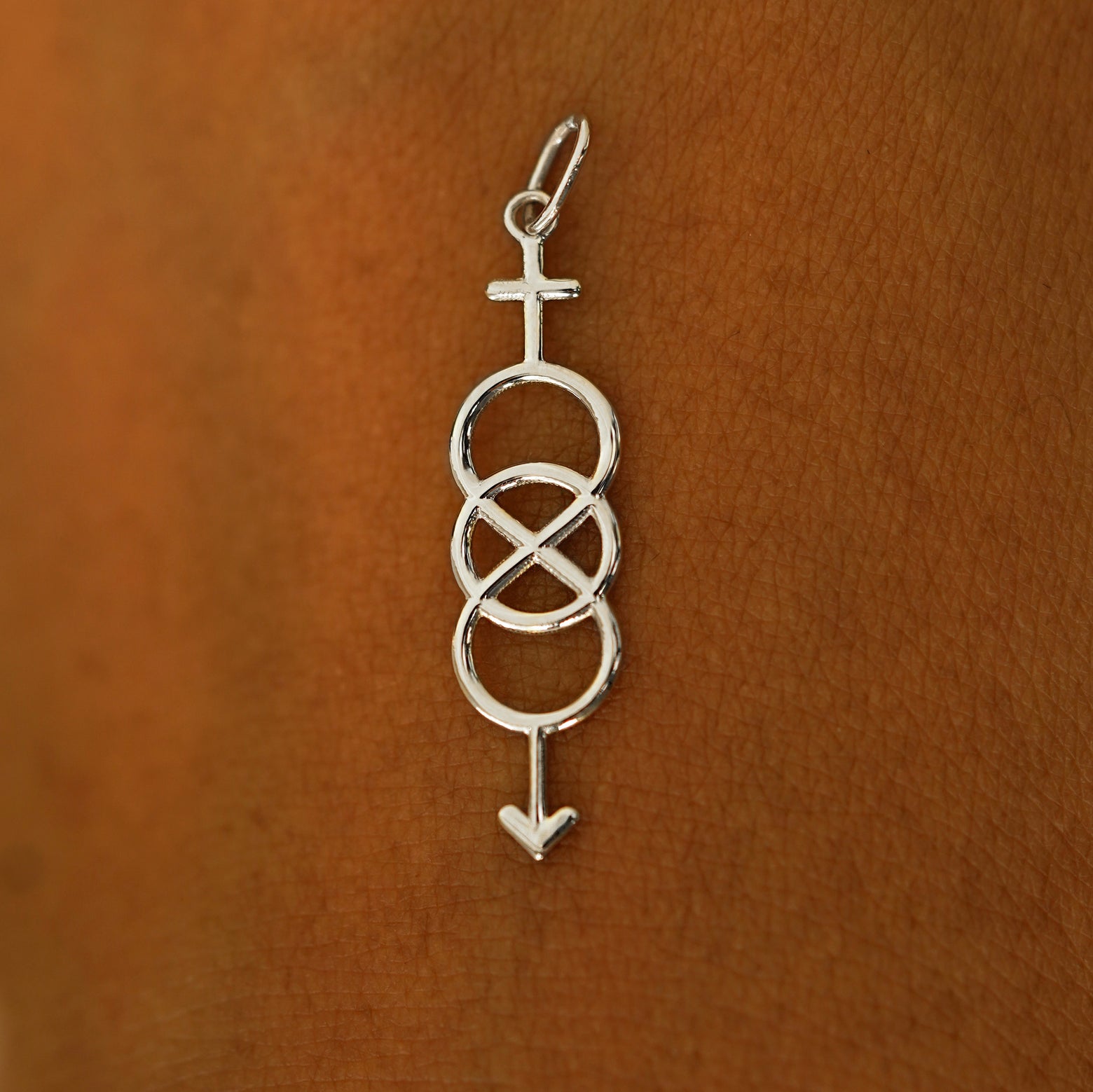 A solid 14k white gold Bisexual Symbol Charm resting on the back of a model's hand