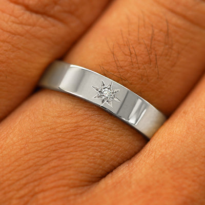 Close up view of a model's hand wearing a solid white gold Engraved Star Diamond Band