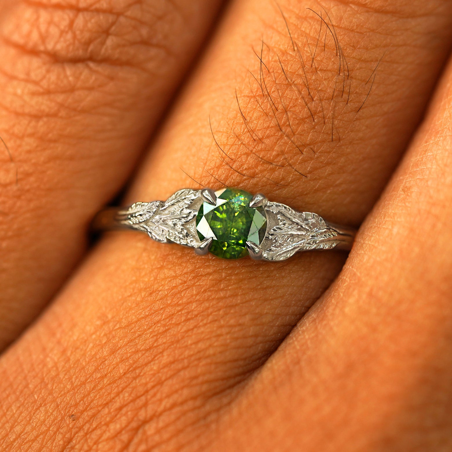 Close up view of a model's fingers wearing a 14k white gold Green Diamond Leaves Ring