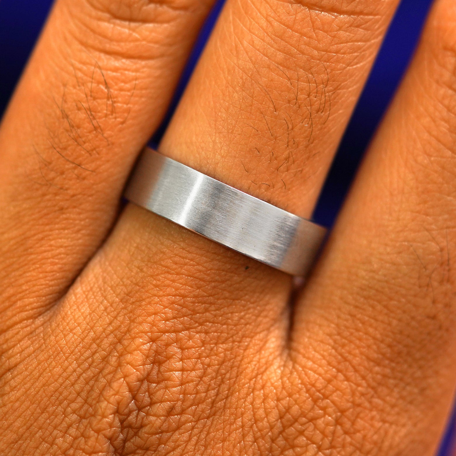 Close up view of a model's fingers wearing a 14k white gold Industrial Matte Band