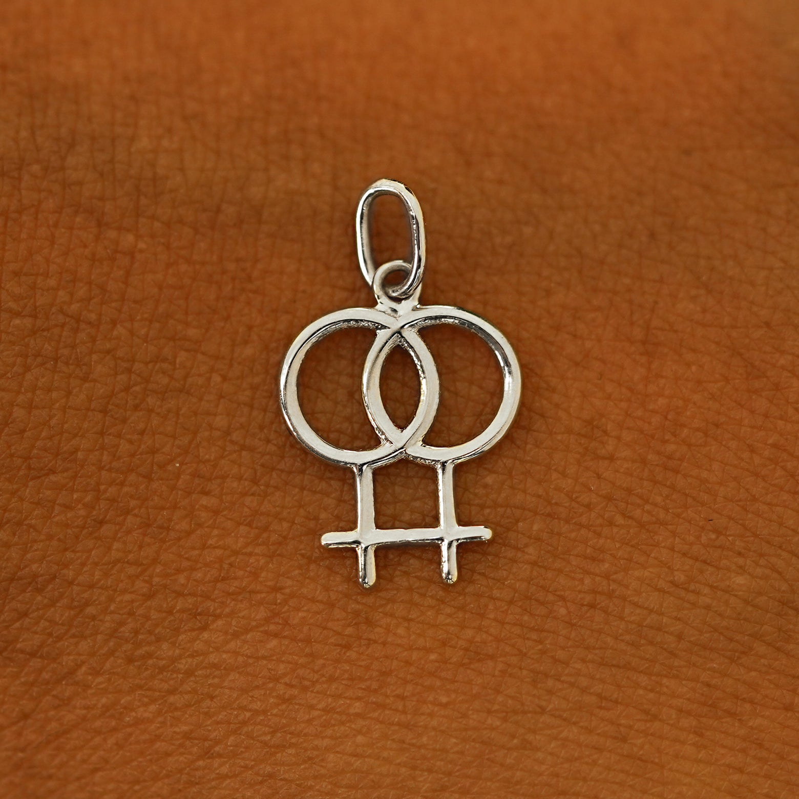 A solid 14k white gold Lesbian Symbol Charm resting on the back of a model's hand