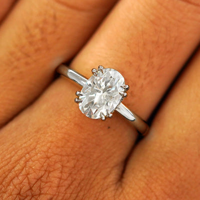 Close up view of a model's fingers wearing a 14k white gold Oval Moissanite Halo Ring