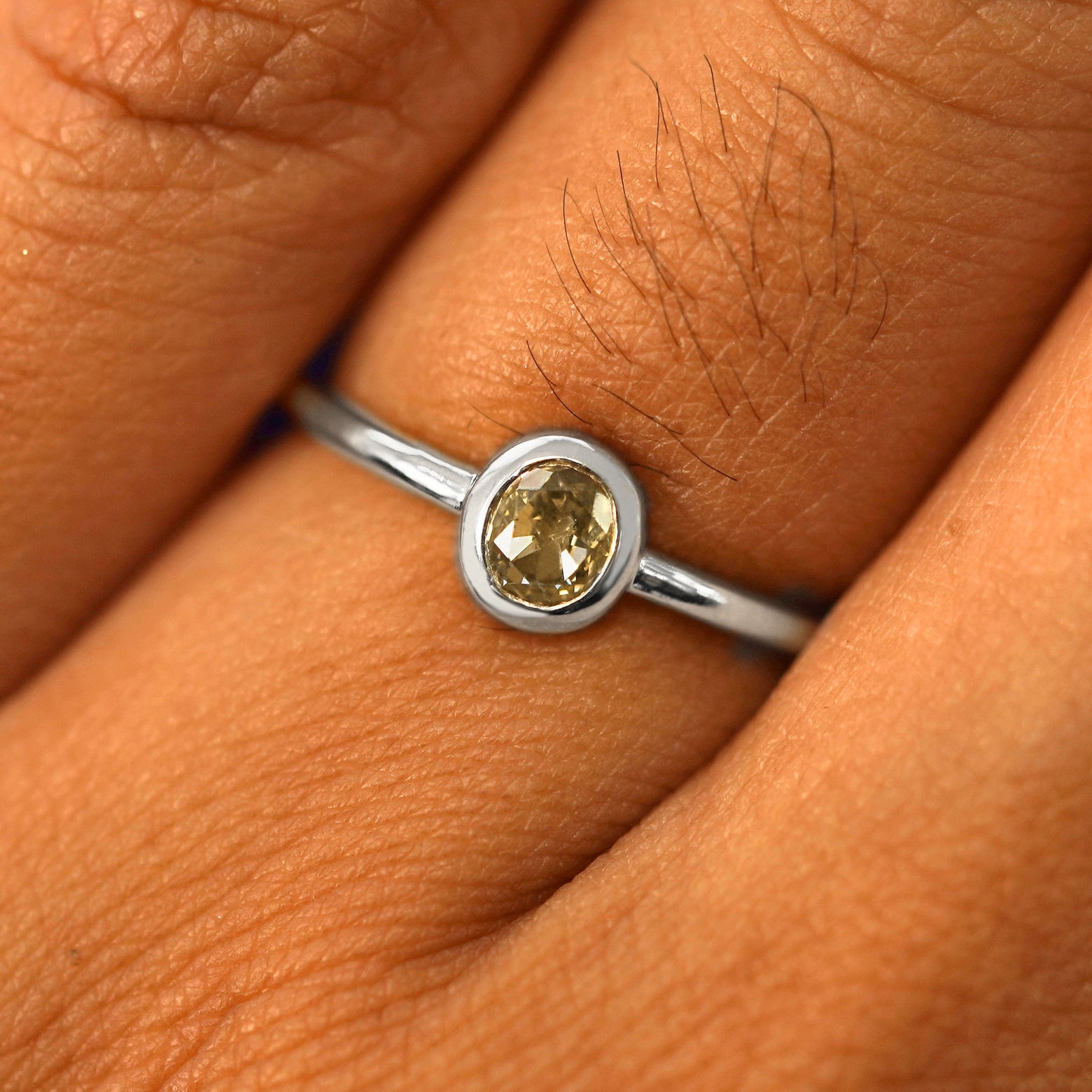 Close up view of a model's fingers wearing a 14k white gold Oval Champagne Diamond Ring