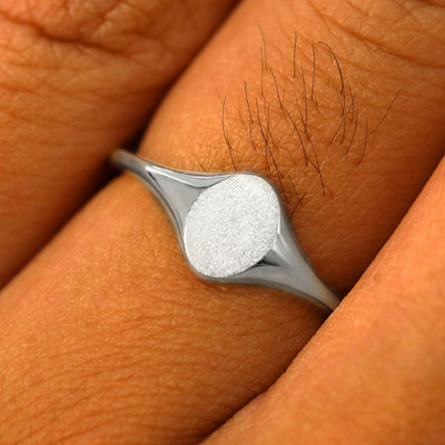 Close up view of a model's fingers wearing a 14k white gold Oval Signet Ring